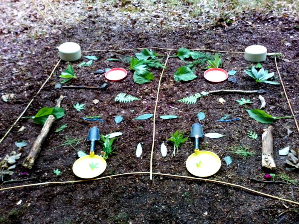 Noughts and crosses laid out on the woodland floor with leaves and natural treasures